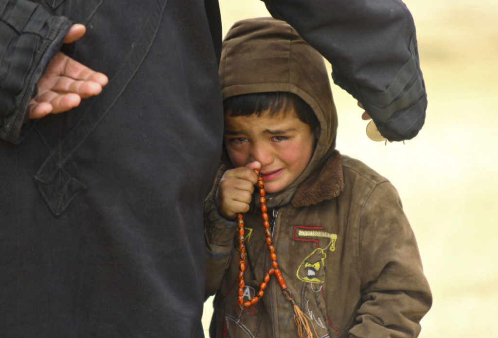 A boy cries while waiting to receive humanitarian aid in the countryside of Idlib