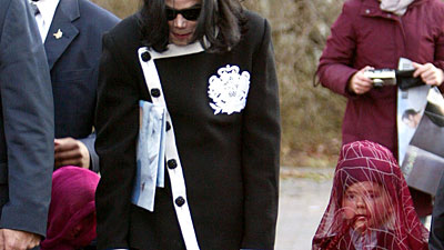 Michael Jackson holds the hands of two children with veils over their heads at Berlin Zoo